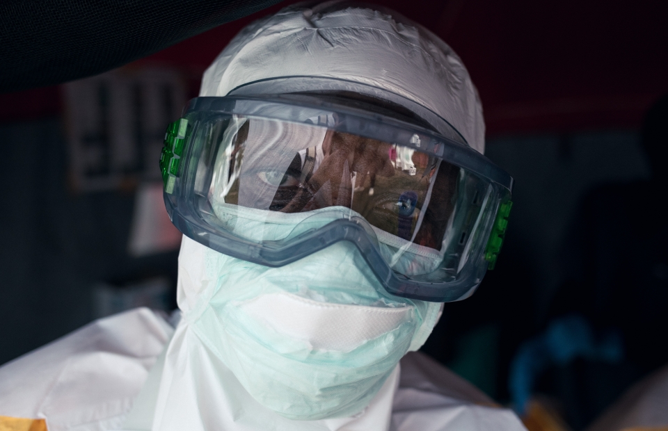 Persoon in beschermende kledij kijkt recht in de camera