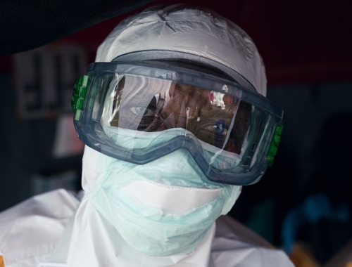 Persoon in beschermende kledij kijkt recht in de camera